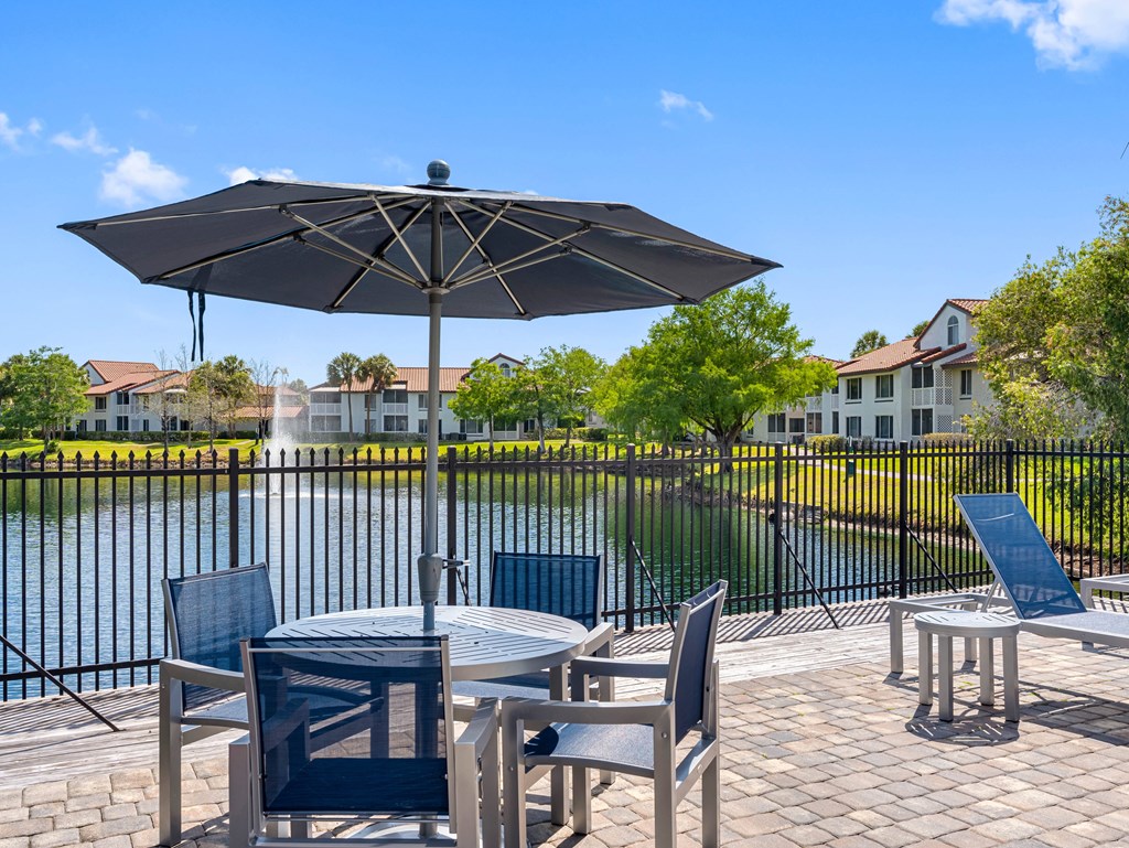 A patio with a table and chairs overlooking a pool.